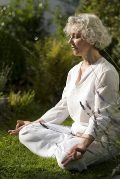 Seniorin meditiert in der Sommersonne