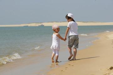 Enfants marchant au bord de la mer en se tenant la main