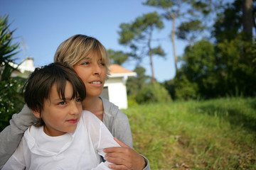 Une femme et un petit garçon dans un jardin regardant au loin