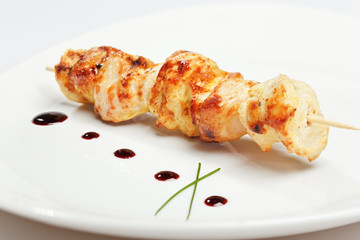 Chicken kebab on skewer in white plate