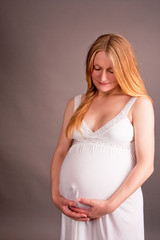 relaxing young pretty pregnant blonde in white dress isolated