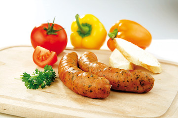 Two sausages and vegetable on a wooden board