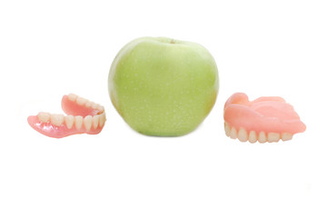 Dentures with green apple, isolated on a white background