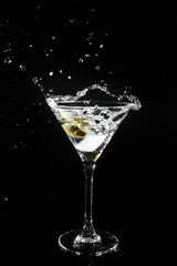 Splashing olive into a martini glass