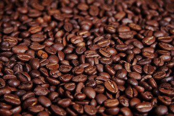 Menge an hell beleuchtetem glänzendem Kaffee, geröstete Kaffeebohnen Hintergrundmuster mit Schärfeverlauf / Tiefenunschärfe