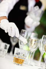 Ice cube droping off in the brandy glass by waiter