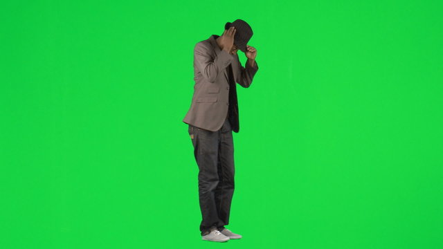Young man dancing with a hat and a green background