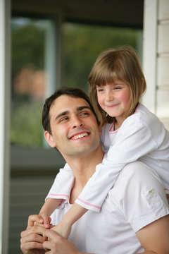 homme souriant portant une petite fille sur son dos