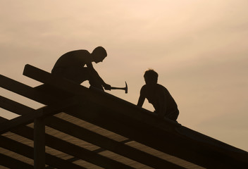 Shot of a carpenter swinging his hammer constructing an roof.