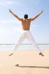 Fototapeta premium Mann springt am Strand in die Luft