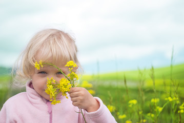 Little girl smelling flower in field