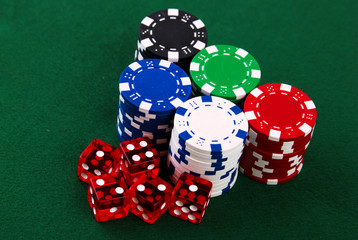 Stacks of casino chips and dice on green