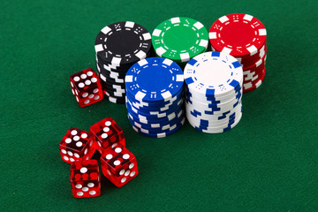 Stacks of casino chips and dice on green