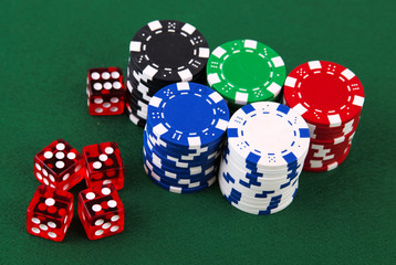 Stacks of casino chips and dice on green