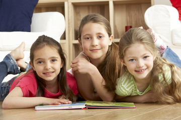 Three Young Girls Reading Book at Home