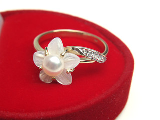 Golden ring with pearl over red box