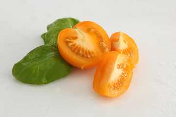 gelbe Tomaten mit Basilikum auf weiss