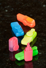 Miniature highlighters on reflective black surface