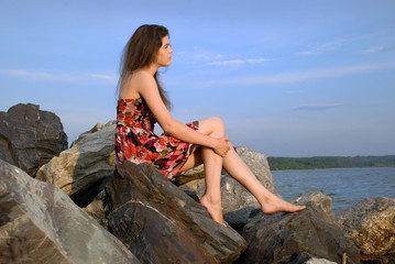 Beautiful girl sit on rock on sea coast