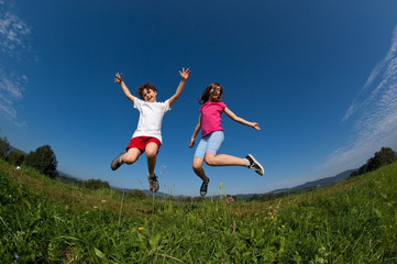 Kids jumping, running against blue sky