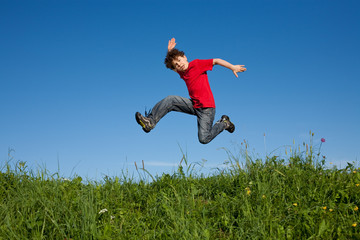 Boy jumping, running against blue sky