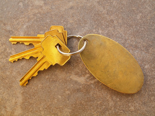 3 Gold Keys and keychain on tile