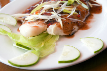A fresh fish and green onions dish on a white china plate