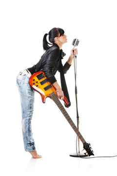 Rock-n-roll girl holding a guitar singing into retro microphone