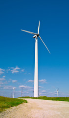 Fototapeta premium Wind power station - wind turbine against the blue sky