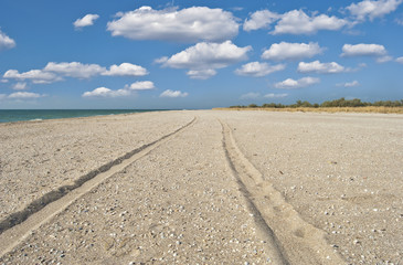 Trace left the car on sand - road to the sky on a beach