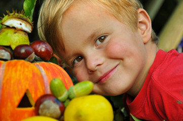 Fototapeta na wymiar Kind freut sich über die Herbstfrüchte