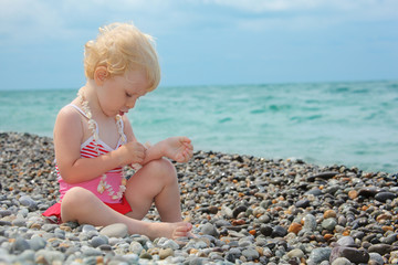 child sits on pebble beach