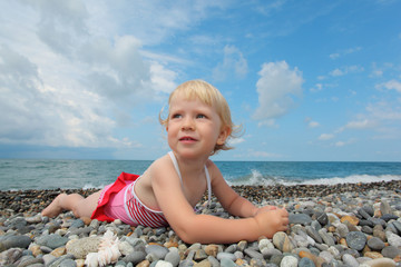 child lies on pebble beach