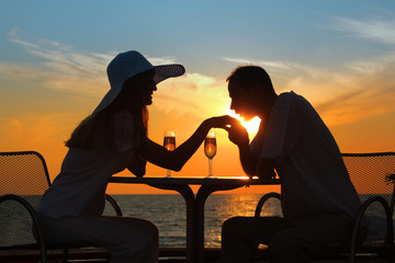 Fototapeta na wymiar man kisses hand to woman on sunset behind table outside