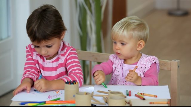 Fillettes faisant du coloriage assises &agrave; un pupitre