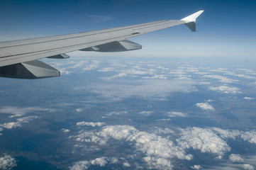 Fototapeta na wymiar Airplane wings and higher clouds landscape