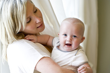 Mother holding happy seven month old baby