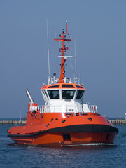 A huge orange tugboat in a harbor