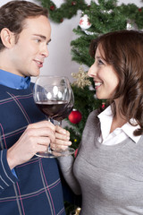 paar stösst unterm weihnachtsbaum an