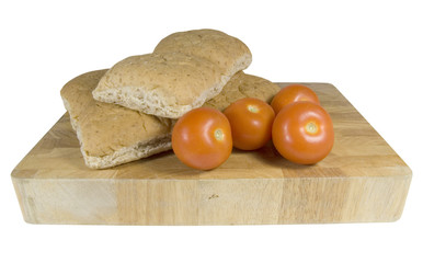bread rolls and tomatoes on chopping board on white