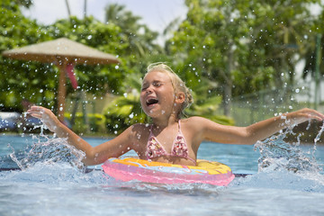 Little girl having fun splashing water in a pool