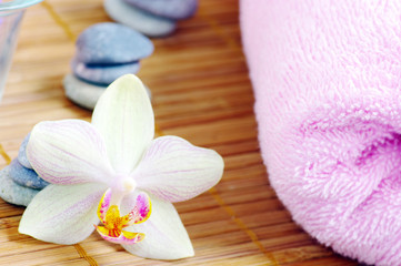 Obraz na płótnie Canvas spa with orchids towels and stones on wet wooden background