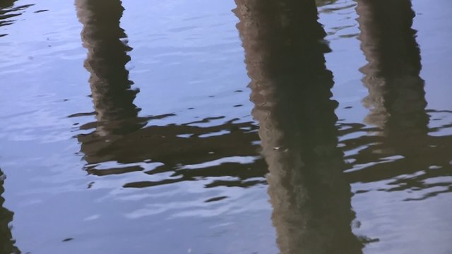 Reflections of metal bridge base columns in  water ripples