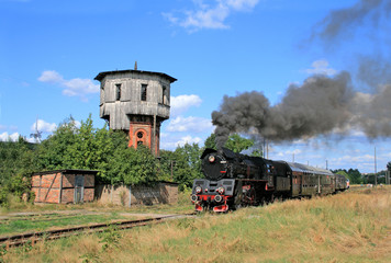 Fototapeta premium Old retro steam train starting from the small station