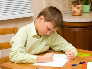 Young boy thinking, doing his homework