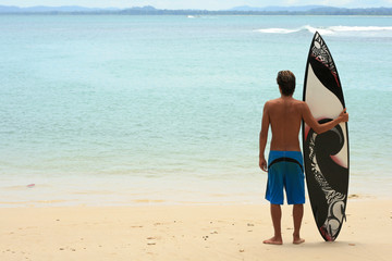 Surfer standing on beach with funky arty surfboard