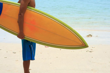 Surfer on beach with vintage retro orange surfboard