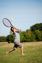 Young boy hitting tennis ball