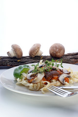Pasta with mushroom and meat on a white plate