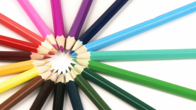 Close-up of colour pencils in a circle turning against white
